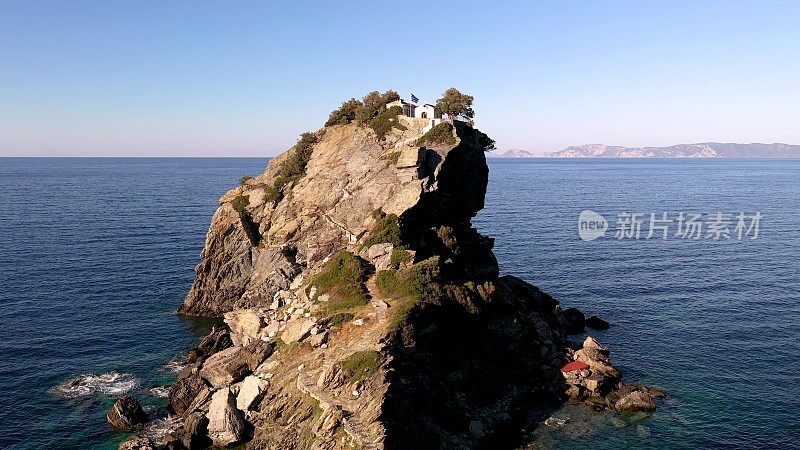 无人机拍摄的风景如画的圣约翰教堂建在著名的Mama Mia电影悬崖上，Skopelos岛，斯波拉迪斯，希腊。日落。